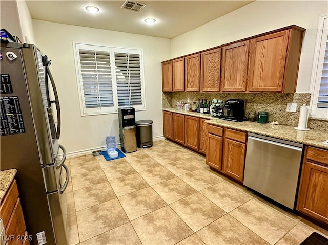 kitchen with light stone countertops, light tile patterned floors, appliances with stainless steel finishes, and tasteful backsplash