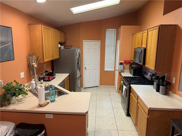 kitchen featuring light tile patterned floors, a peninsula, vaulted ceiling, stainless steel appliances, and a sink