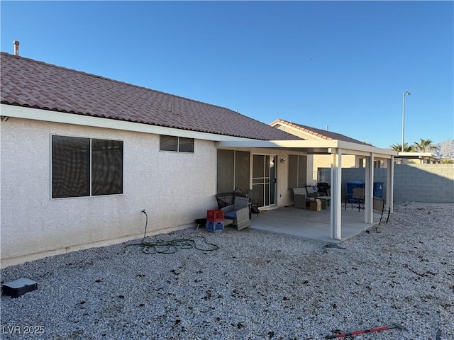 rear view of property with a patio, fence, and stucco siding