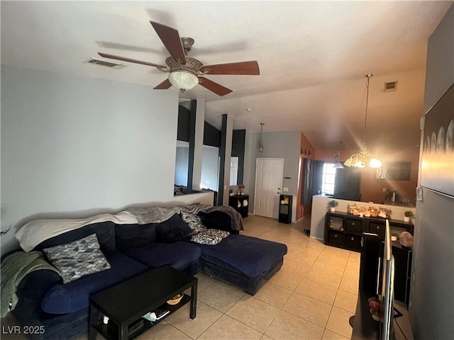 living area featuring light tile patterned floors, visible vents, vaulted ceiling, and ceiling fan with notable chandelier