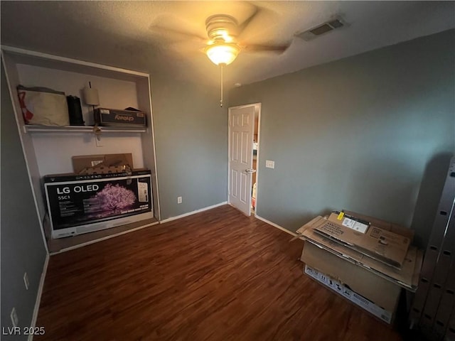 interior space with baseboards, visible vents, ceiling fan, and wood finished floors