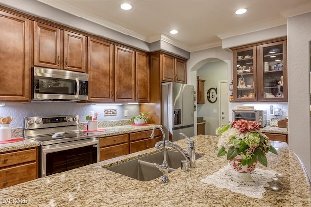 kitchen featuring crown molding, light stone counters, sink, and stainless steel appliances