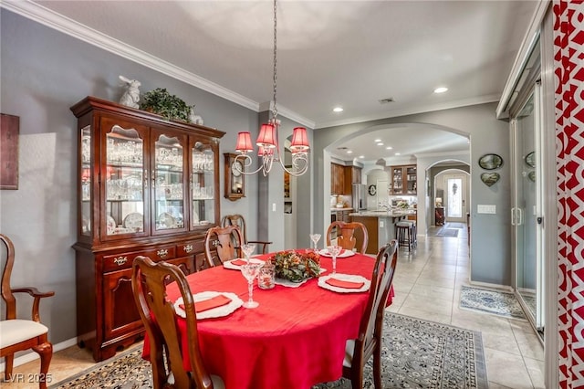 tiled dining area featuring ornamental molding and an inviting chandelier