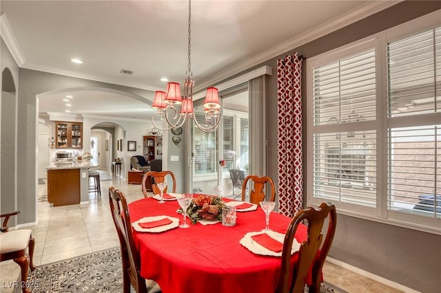 tiled dining room featuring ornamental molding and an inviting chandelier