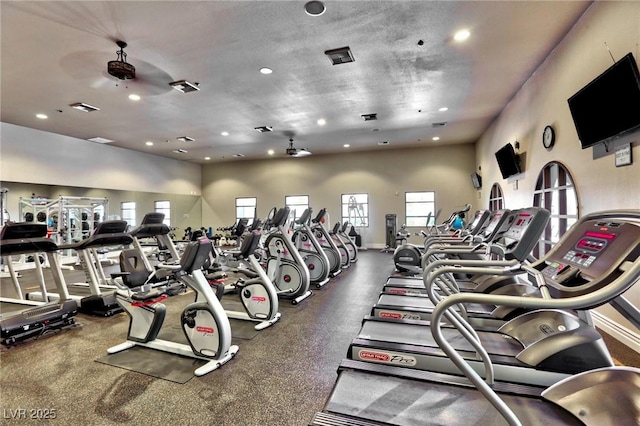 exercise room with ceiling fan and a towering ceiling