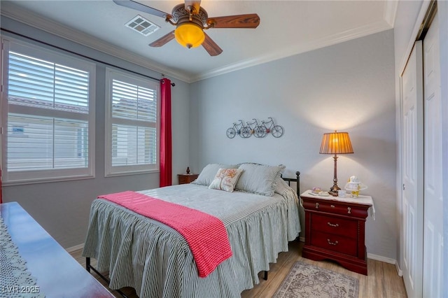 bedroom featuring light hardwood / wood-style flooring, a closet, ornamental molding, and ceiling fan