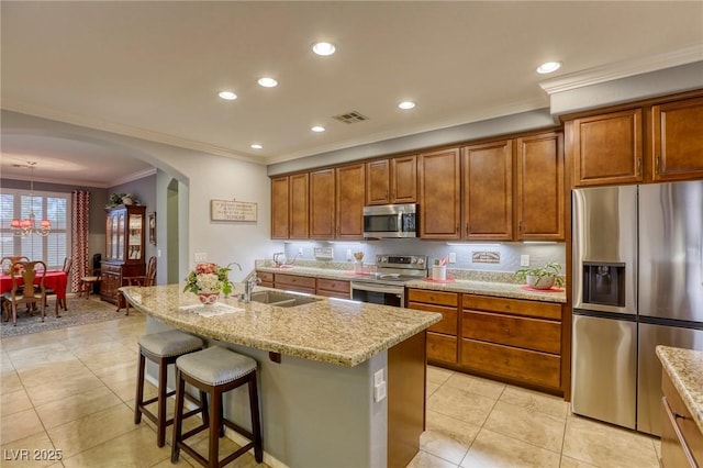 kitchen featuring sink, a breakfast bar area, an island with sink, light stone counters, and stainless steel appliances