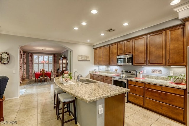 kitchen featuring ornamental molding, a breakfast bar, stainless steel appliances, a kitchen island with sink, and sink