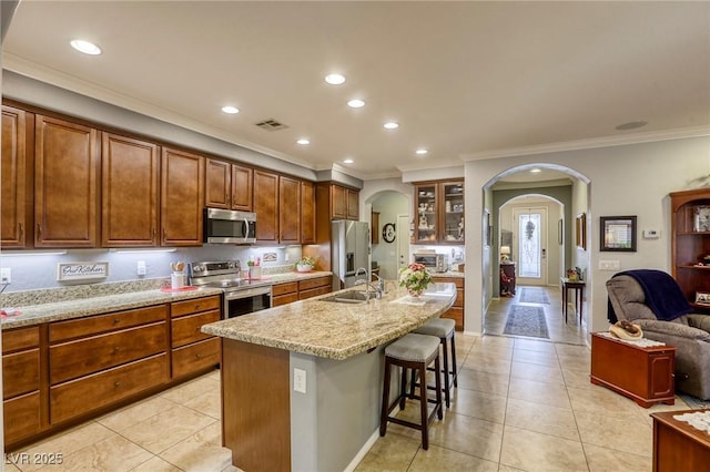 kitchen with sink, crown molding, a kitchen bar, a kitchen island with sink, and appliances with stainless steel finishes