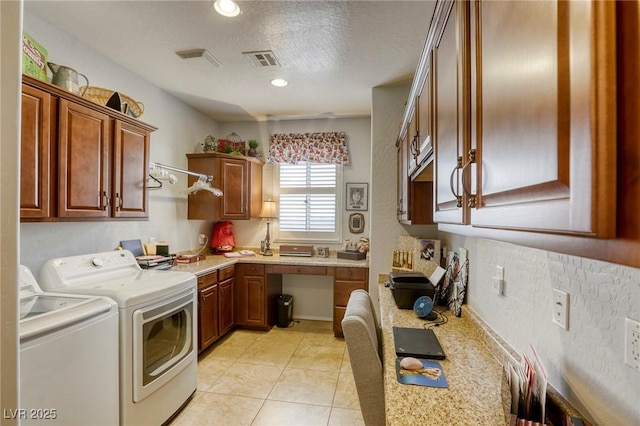 laundry room featuring cabinets, a textured ceiling, light tile patterned flooring, and washing machine and clothes dryer