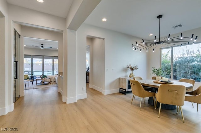 dining room with ceiling fan with notable chandelier and light wood-type flooring