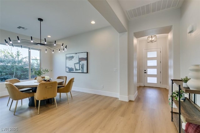 dining room with light hardwood / wood-style floors and an inviting chandelier