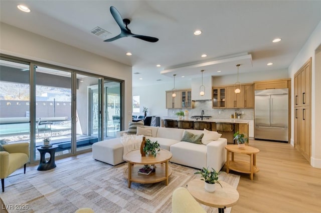 living room featuring ceiling fan, light wood-type flooring, and sink