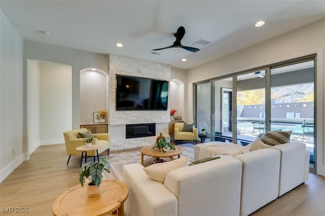 living room featuring a fireplace, light hardwood / wood-style flooring, and ceiling fan