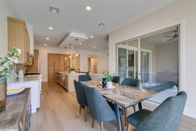 dining space featuring ceiling fan, light hardwood / wood-style floors, and sink