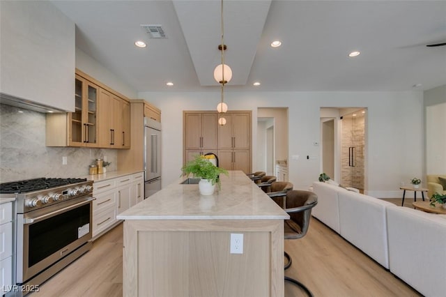 kitchen with light brown cabinets, a center island, a kitchen breakfast bar, pendant lighting, and high end appliances