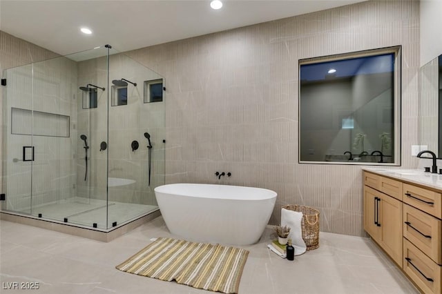 bathroom featuring tile patterned flooring, vanity, tile walls, and shower with separate bathtub