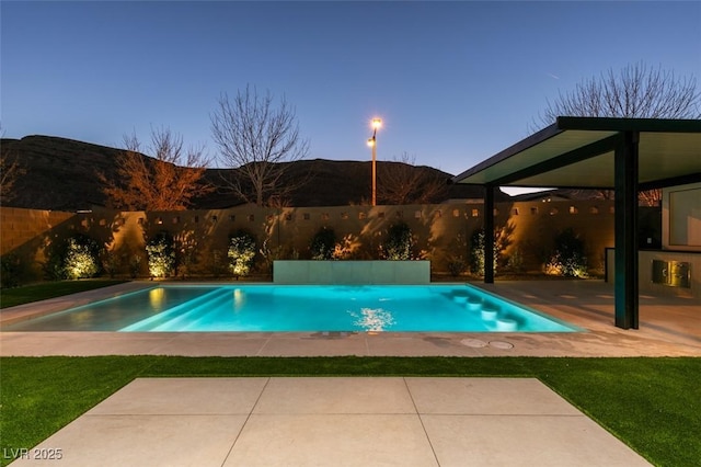 pool at dusk with a patio area