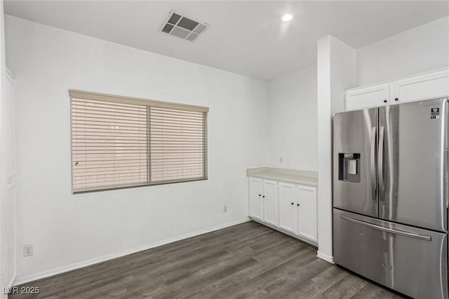 kitchen with visible vents, baseboards, dark wood-style floors, stainless steel fridge, and white cabinetry