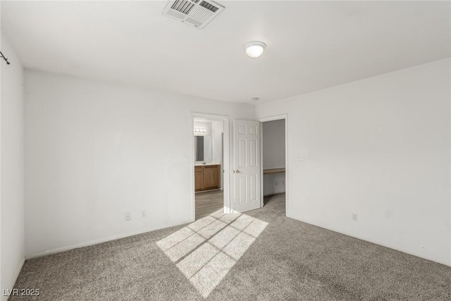 unfurnished bedroom with ensuite bath, light colored carpet, and visible vents