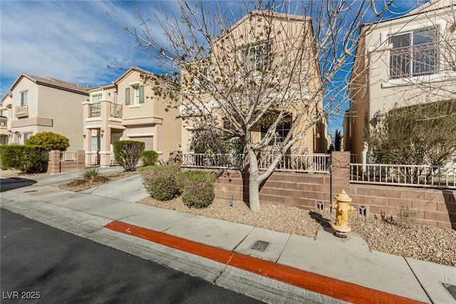 view of front facade with a fenced front yard, a residential view, stucco siding, and a balcony