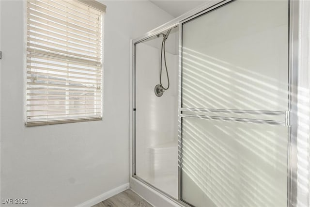 bathroom with a stall shower, baseboards, and wood finished floors