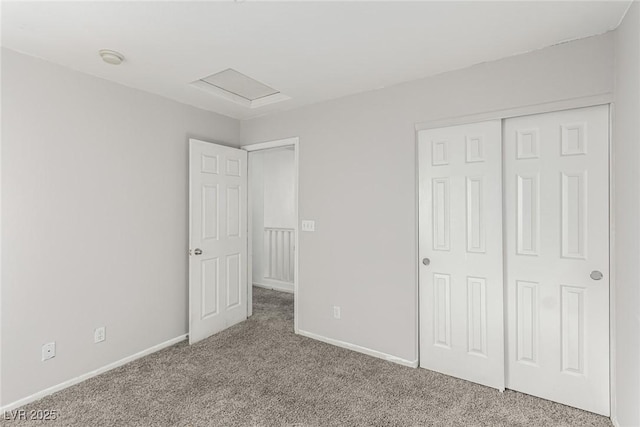 unfurnished bedroom featuring attic access, carpet flooring, baseboards, and a closet