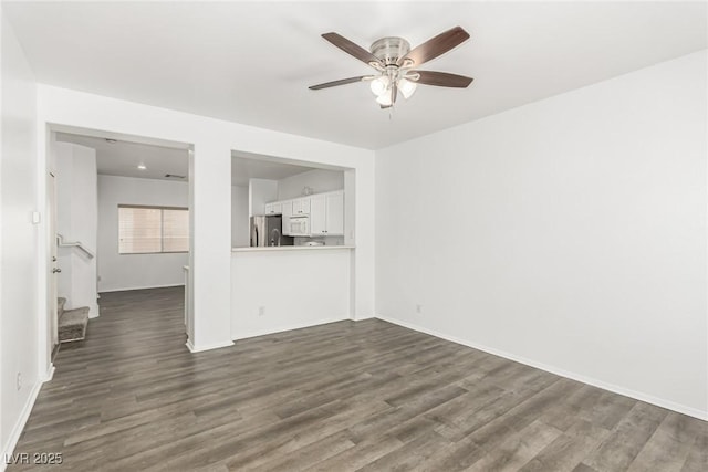 unfurnished living room with baseboards, stairs, dark wood-type flooring, and ceiling fan