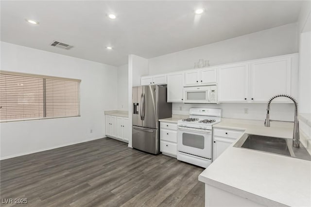 kitchen featuring visible vents, a sink, white appliances, white cabinets, and dark wood-style flooring