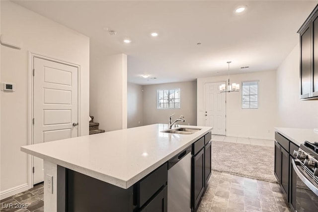 kitchen with stainless steel appliances, a kitchen island with sink, sink, pendant lighting, and a notable chandelier