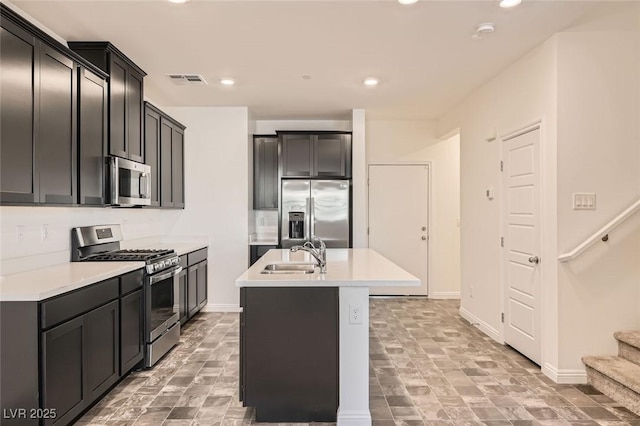 kitchen with a kitchen island with sink, sink, and appliances with stainless steel finishes