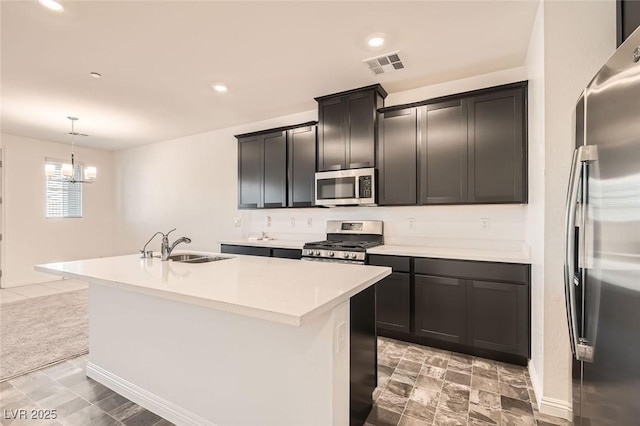 kitchen featuring a kitchen island with sink, hanging light fixtures, stainless steel appliances, and an inviting chandelier