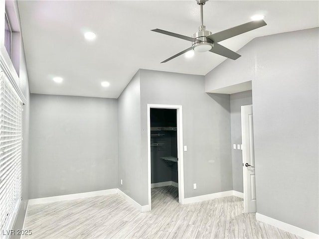 unfurnished bedroom featuring light wood-type flooring, vaulted ceiling, ceiling fan, a spacious closet, and a closet