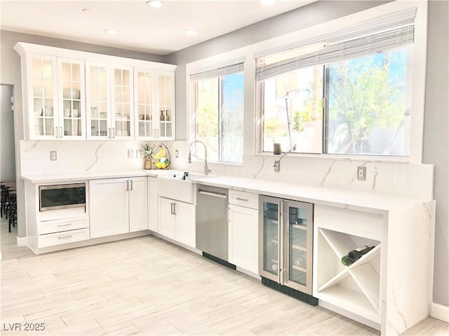 kitchen featuring white cabinetry, sink, beverage cooler, light hardwood / wood-style floors, and appliances with stainless steel finishes