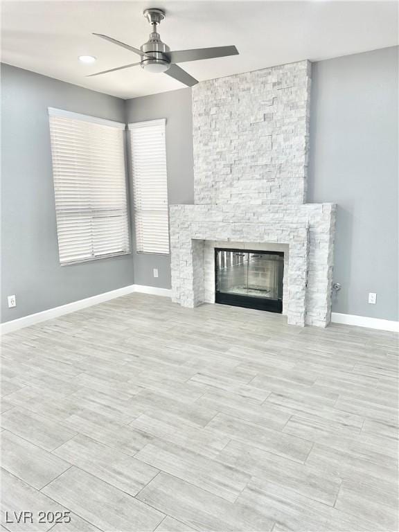 unfurnished living room with ceiling fan and a stone fireplace