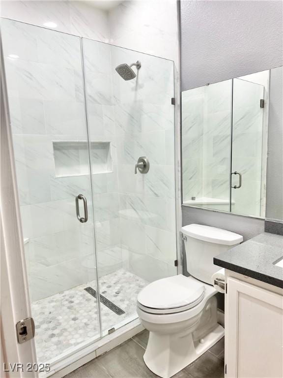 bathroom featuring vanity, toilet, and a shower with door