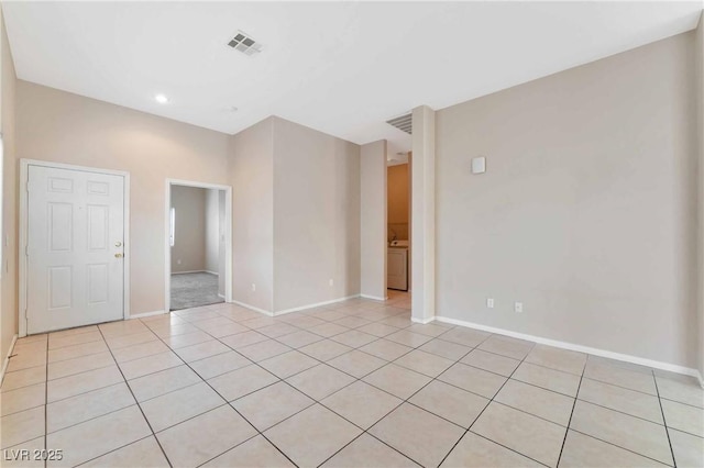 empty room with washer / dryer and light tile patterned flooring