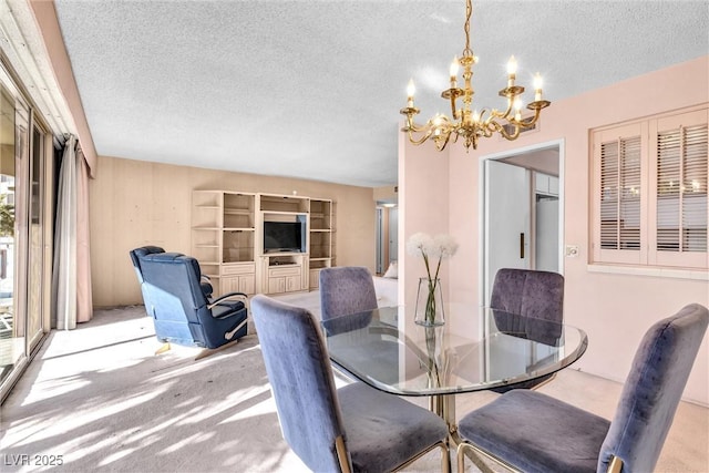 dining room featuring a chandelier, light carpet, and a textured ceiling