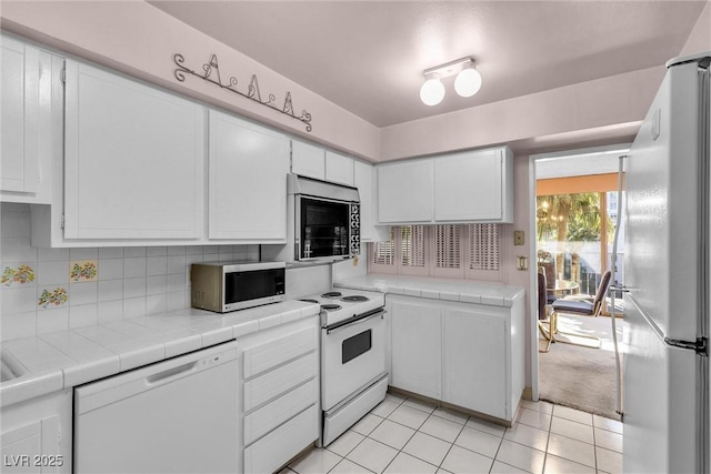 kitchen with white cabinetry, white appliances, tile counters, and decorative backsplash