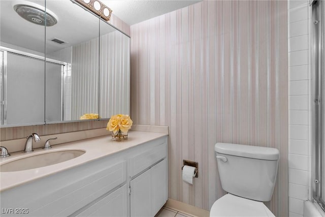 bathroom featuring tile patterned flooring, vanity, walk in shower, toilet, and a textured ceiling