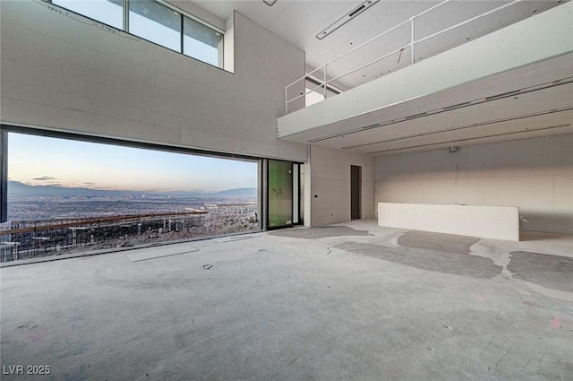 unfurnished room with a mountain view, concrete flooring, and a high ceiling