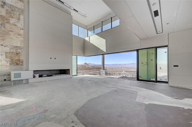 unfurnished living room featuring a mountain view, a towering ceiling, and concrete floors