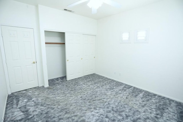 unfurnished bedroom with ceiling fan, dark carpet, and a closet