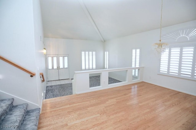 unfurnished living room with vaulted ceiling, an inviting chandelier, and wood-type flooring