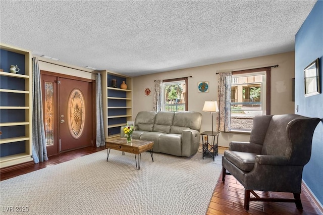 living room featuring plenty of natural light, a textured ceiling, and built in shelves