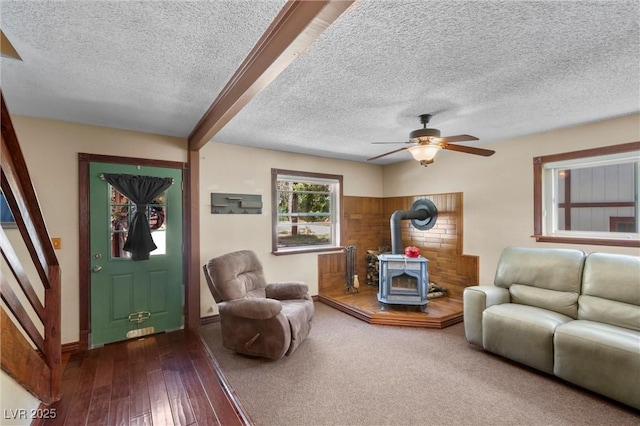 living room featuring ceiling fan, dark hardwood / wood-style floors, a wood stove, and a textured ceiling