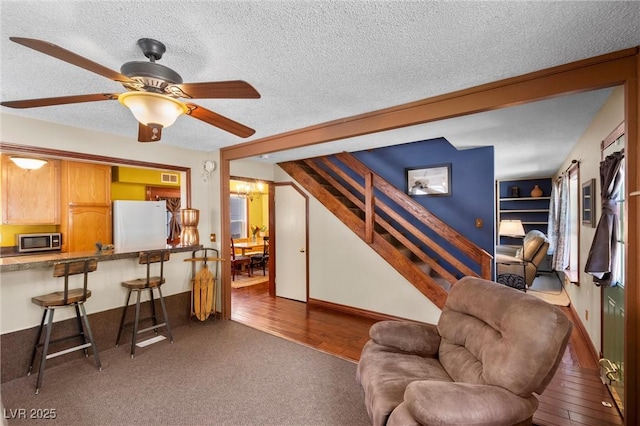 living room featuring a textured ceiling, built in shelves, ceiling fan, and dark wood-type flooring