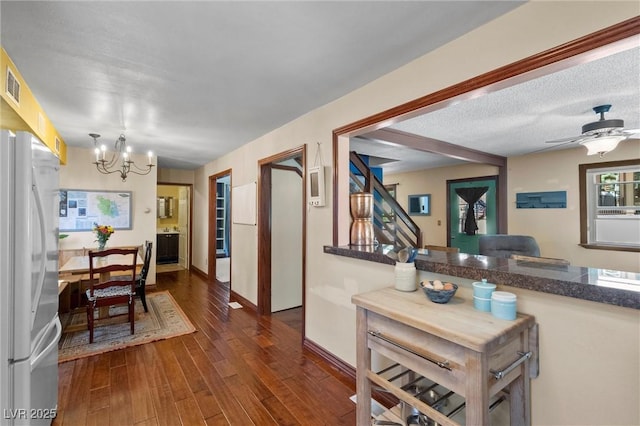 kitchen featuring ceiling fan with notable chandelier, a textured ceiling, decorative light fixtures, white fridge, and dark hardwood / wood-style flooring