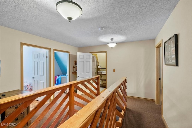 hall with dark carpet and a textured ceiling