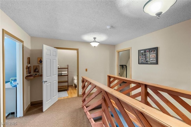 hall with light carpet and a textured ceiling